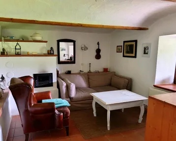 Rustikales Wohnzimmer mit Kamin, bequemen Möbeln und Terrakottafliesen auf dem Boden.