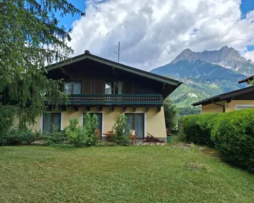 Traditionelles Haus im alpinen Stil mit Garten, Balkon und beeindruckendem Bergblick.