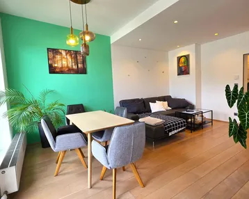 Helles Wohn- und Esszimmer mit modernem Design, grüner Akzentwand und Holzboden.