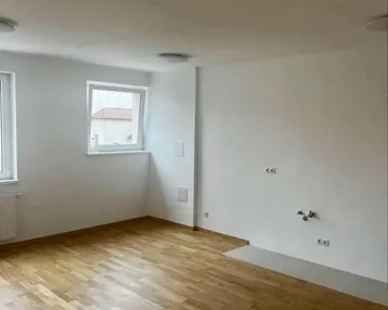 Helles Zimmer mit Parkettboden und weißen Wänden, bereit für die Einrichtung einer Küche oder eines Wohnbereichs.