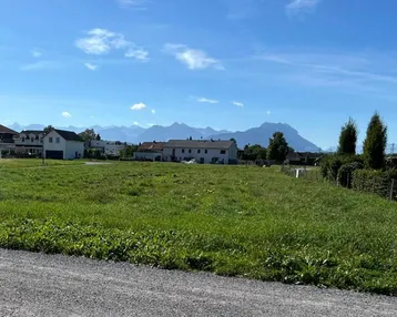 Weitläufiges Grundstück mit Blick auf die umliegende Bebauung und die Berge im Hintergrund.