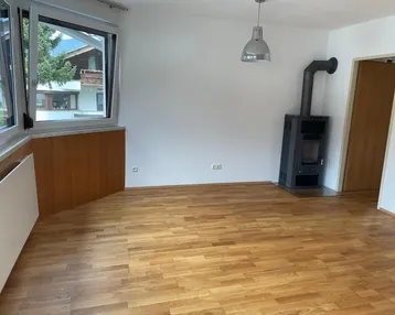 Helles Zimmer mit Holzboden und Kaminofen, bietet vielseitige Nutzungsmöglichkeiten.