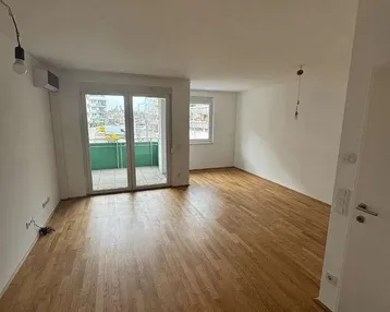 Helles Wohnzimmer mit Parkettboden und Zugang zu einem Balkon, ideal für entspannte Stunden.
