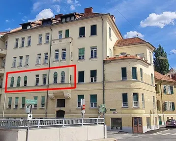 Außenansicht eines Mehrfamilienhauses mit klassischer Architektur und hervorgehobenen Fenstern.