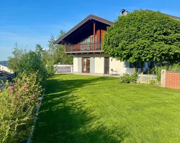 Gepflegter Garten mit weitläufiger Rasenfläche und Blick auf das charmante Haus mit Balkon.