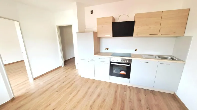 Neue, helle Einbauküche mit modernen Geräten und Laminatboden in einem offenen Wohnbereich.
