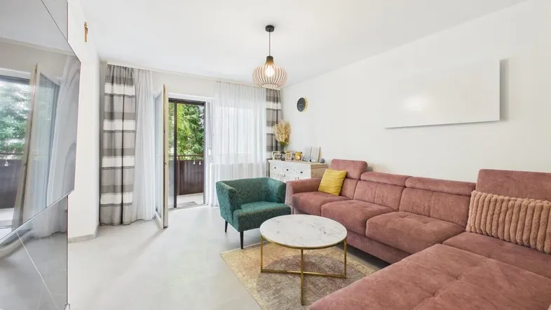 Helles Wohnzimmer mit gemütlichem Sofa, modernem Couchtisch und Zugang zum Balkon.