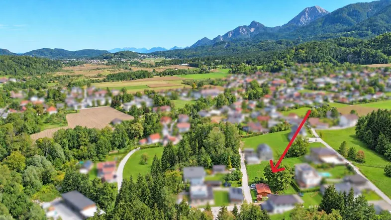 Luftaufnahme einer ländlichen Gegend mit Bergen im Hintergrund und einem markierten Grundstück.