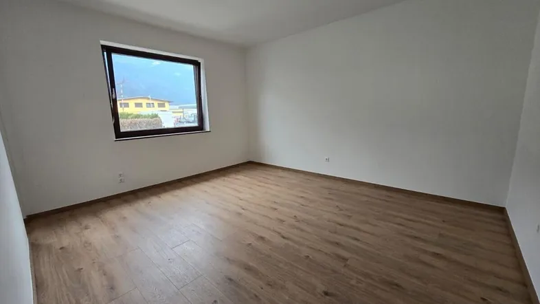 Heller, leerer Raum mit Laminatboden und einem Fenster, ideal als Schlafzimmer nutzbar.