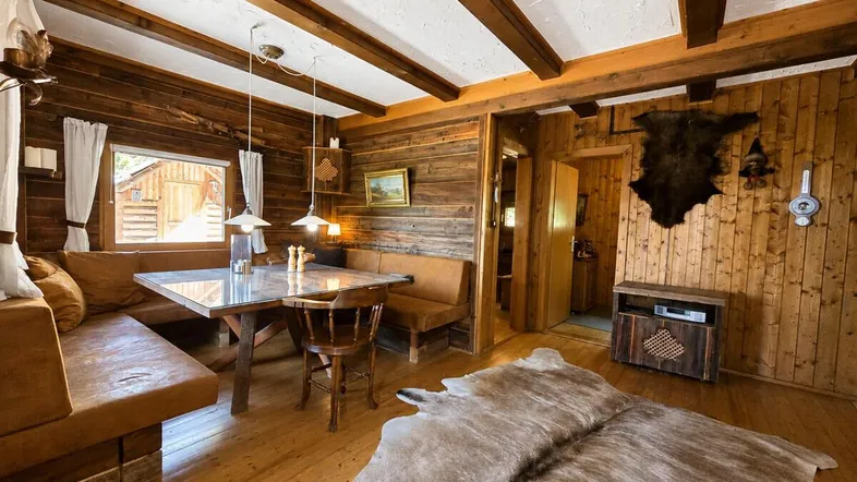 Gemütlicher Wohn-Essbereich im alpinen Stil mit Holzbalken, Holzvertäfelung und rustikalen Möbeln.