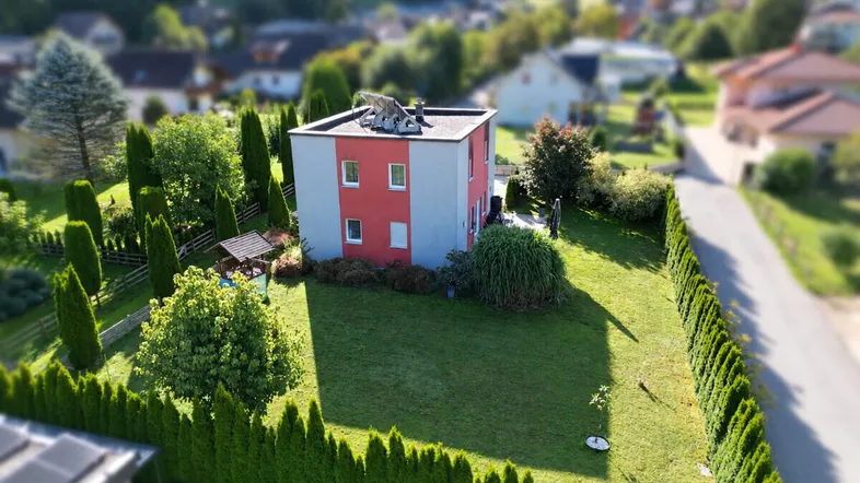 Luftaufnahme eines modernen Hauses mit großem, gepflegtem Rasen und umgebender Hecke.