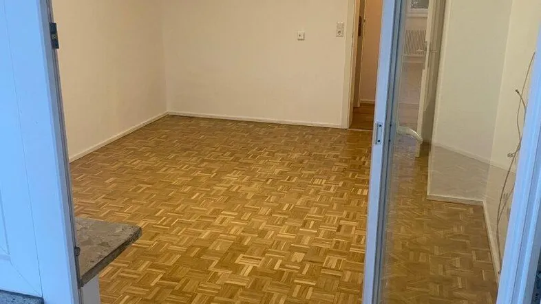 Helles, leeres Zimmer mit Parkettboden und Zugang zu einem Balkon, bereit zur individuellen Gestaltung.