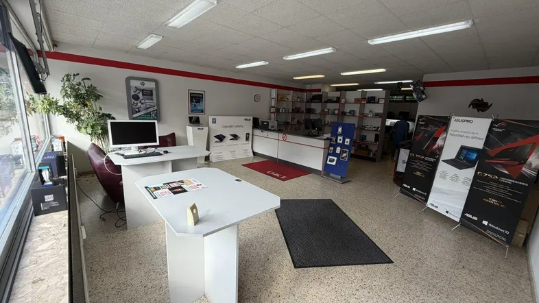 Geräumiger Verkaufsraum mit großen Fenstern, Schreibtischen und Ausstellungsflächen für Elektronikprodukte.