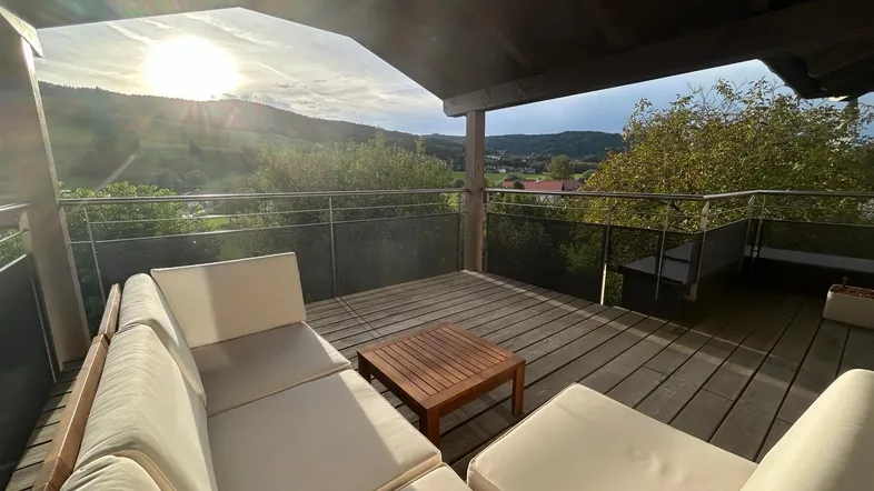 Geräumige überdachte Terrasse mit bequemen Sitzmöbeln und weitem Blick auf die umliegende Landschaft.