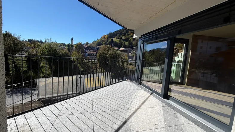 Geräumiger Balkon mit Fliesenboden und weitem Blick auf die umliegende Berglandschaft.