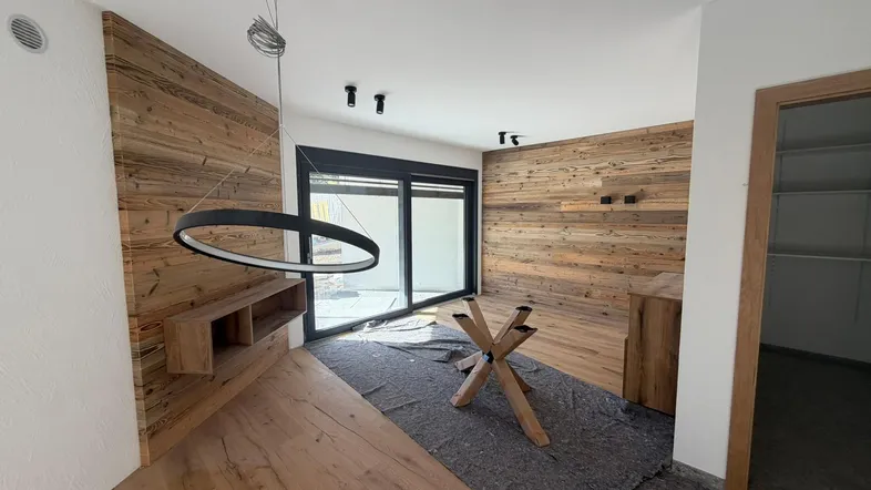 Heller Wohnbereich mit Holzwänden, Holzboden und Zugang zu einem Außenbereich.