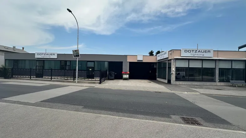 Ansicht des Geschäftsgebäudes von der Straße mit Parkplätzen und Beschilderung unter bewölktem Himmel.