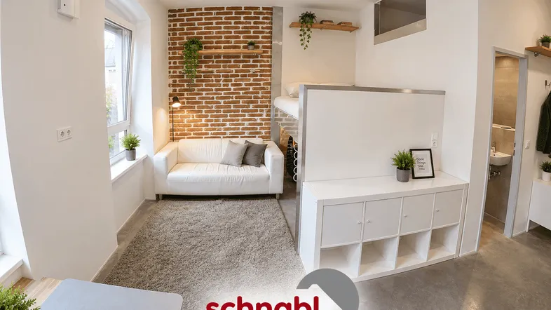 Helles Wohnzimmer in einem Studio-Apartment mit freiliegender Ziegelwand und Hochbett.