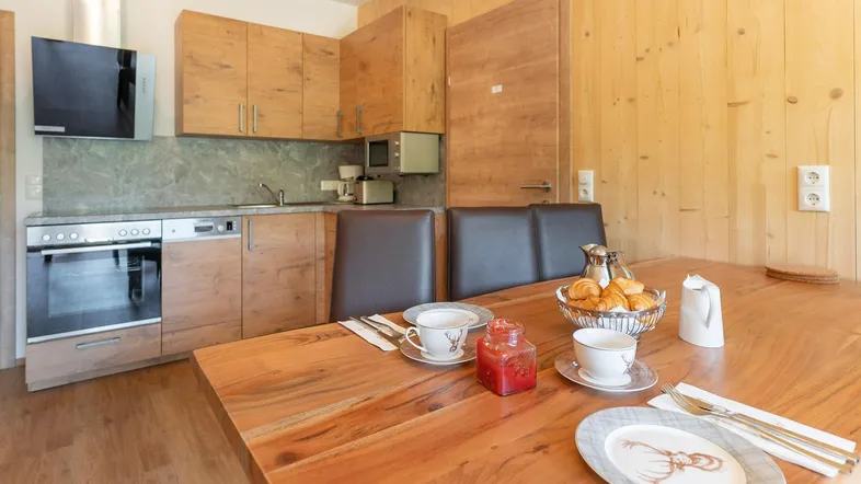 Moderne Küche mit Holzelementen, integrierten Geräten und einem Esstisch für gemütliche Mahlzeiten.