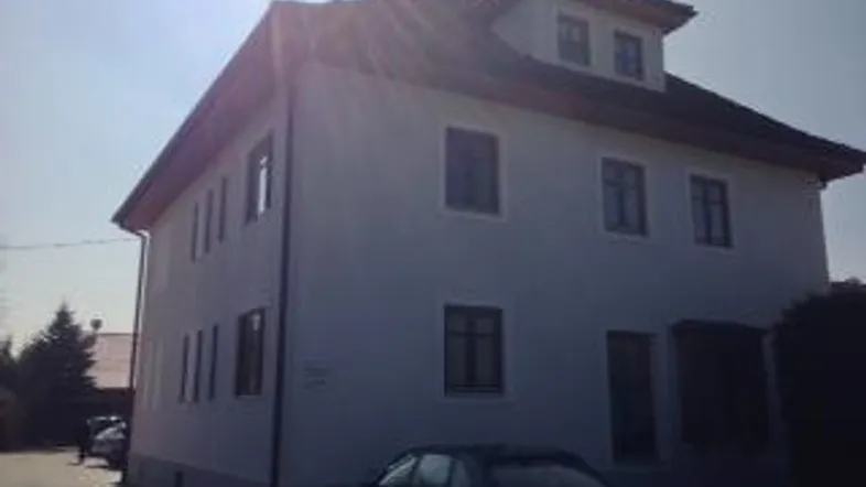 Helles Einfamilienhaus mit klassischer Architektur und Satteldach unter strahlendem Himmel.