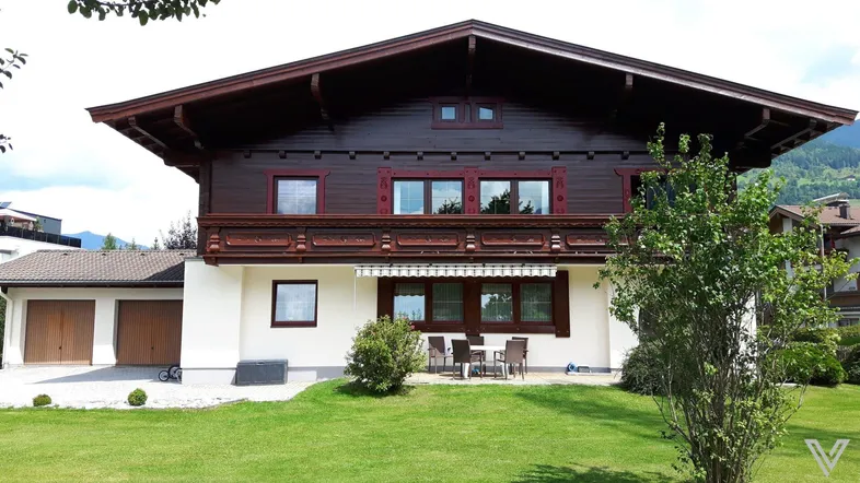 Traditionelles Haus im alpenländischen Stil mit Holzbalkonen und gepflegtem Vorgarten.