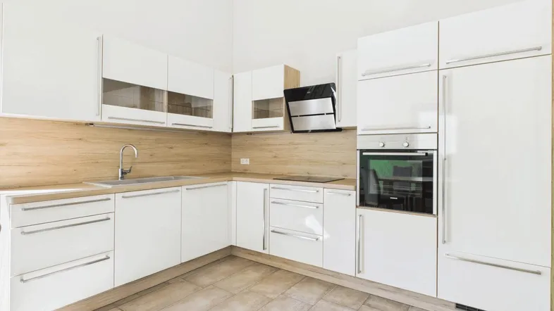 Moderne Einbauküche mit weißen Hochglanzfronten, Holzakzenten und integrierten Geräten.