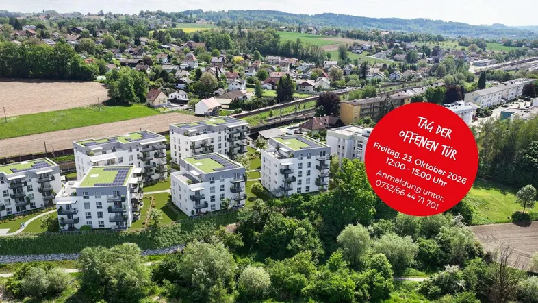 Luftaufnahme von modernen Wohngebäuden mit Gründächern und Solaranlagen in einer grünen Wohngegend.