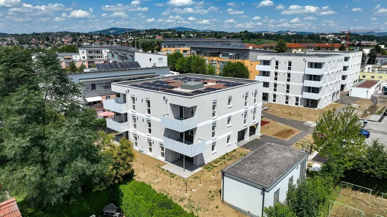 Luftaufnahme von modernen Wohngebäuden mit Flachdächern und umliegender grüner Landschaft.
