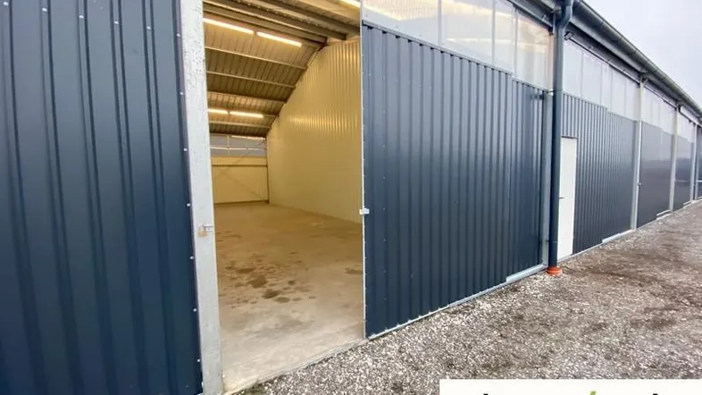 Außenansicht eines modernen Lagergebäudes mit geöffnetem Tor, das den Blick ins Innere freigibt.