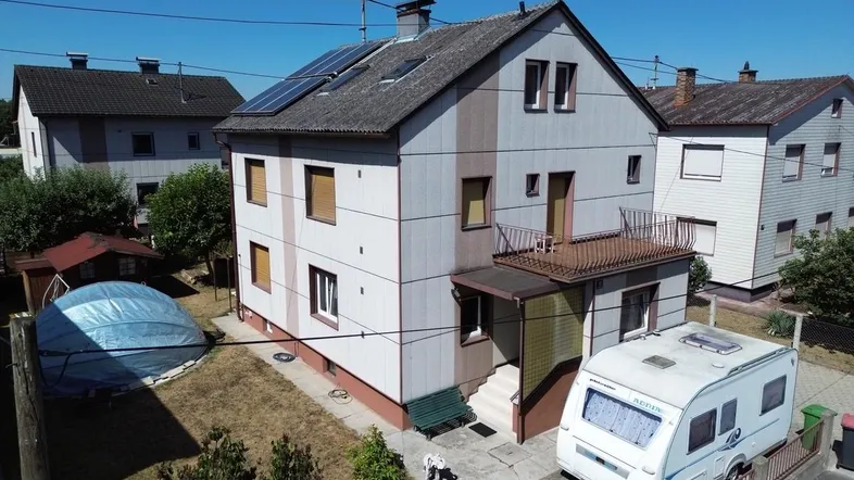 Luftaufnahme eines Einfamilienhauses mit Solaranlage auf dem Dach und Gartenbereich.