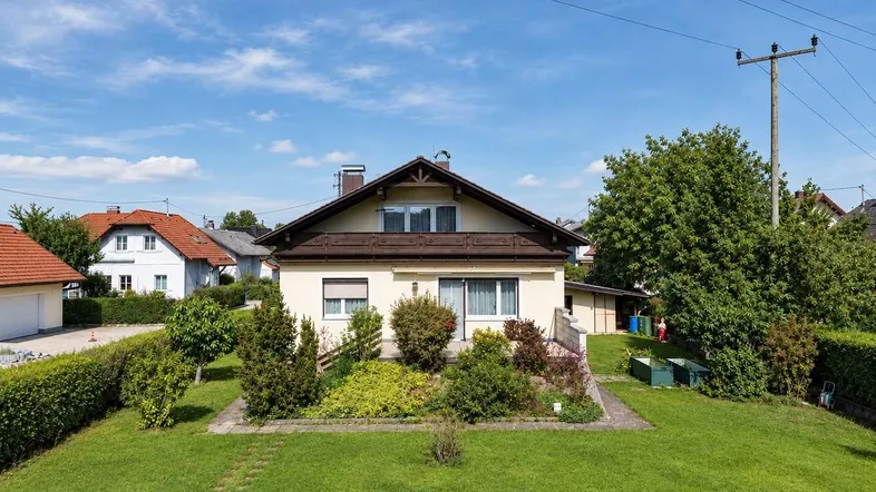 Einfamilienhaus mit gepflegtem Vorgarten und Satteldach in ländlicher Umgebung unter blauem Himmel.