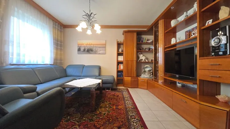 Gemütliches Wohnzimmer mit großer Eckcouch, Holzmöbeln und einem traditionellen Teppich.