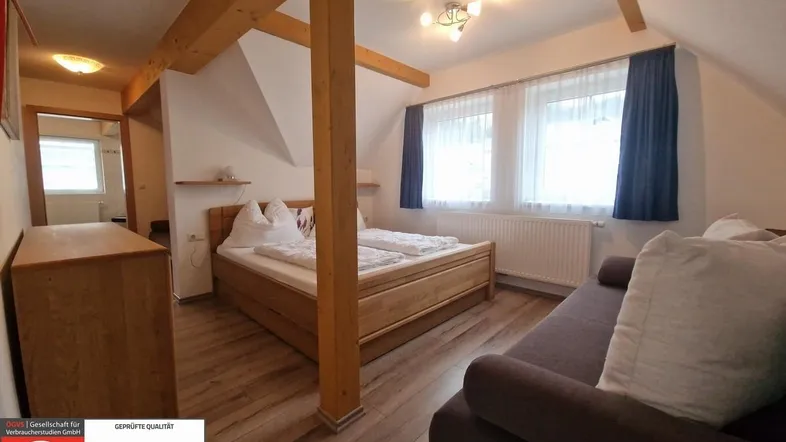 Gemütliches Schlafzimmer mit Holzbalken, Dachschräge und einem bequemen Doppelbett.