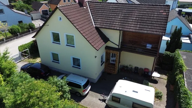 Luftaufnahme eines Einfamilienhauses mit angrenzendem Grundstück und Nachbarschaft.