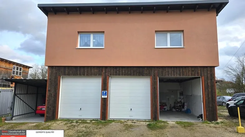 Gebäudeaußenansicht mit drei Garagen, einem Carport und moderner Architektur.