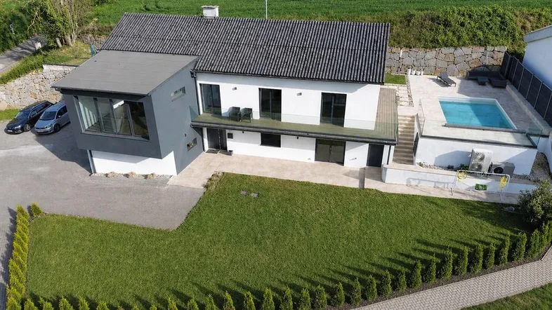 Modernes Einfamilienhaus mit Garten, Pool und weitläufiger Grünfläche in ländlicher Umgebung.