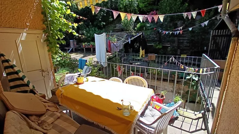 Überdachte Terrasse mit Markise, Esstisch und Blick ins Grüne.