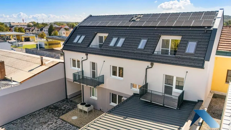 Luftaufnahme eines modernen Mehrfamilienhauses mit Solaranlage auf dem Dach und Balkonen.