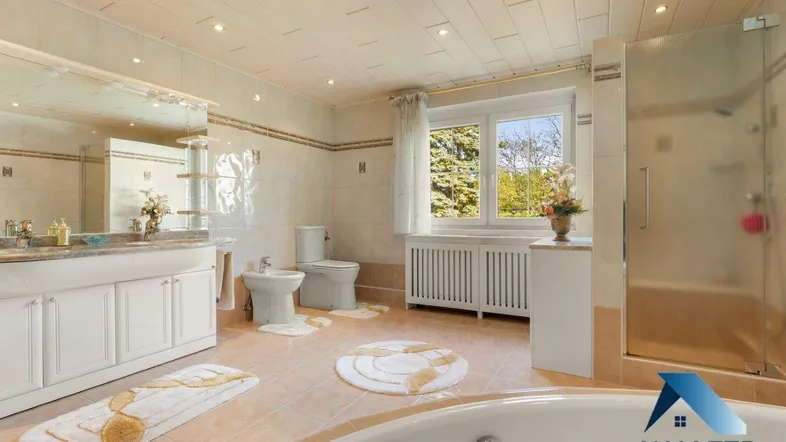 Geräumiges Badezimmer mit Badewanne, Dusche, Doppelwaschbecken und Fenster, hell gefliest.