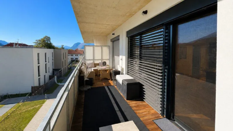 Geräumiger Balkon mit Holzboden, Sitzgelegenheiten und Blick auf die umliegende Landschaft.