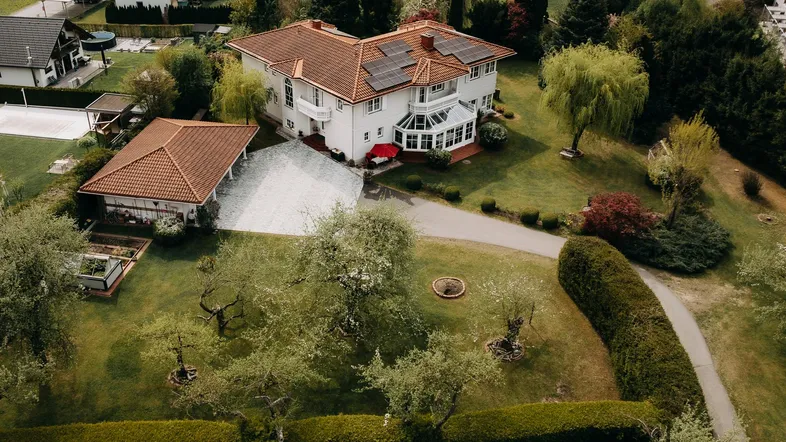Luftaufnahme des Anwesens mit großem Garten, Photovoltaikanlage auf dem Dach und umliegender Landschaft.