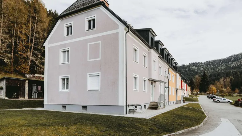 Mehrfamilienhaus mit heller Fassade und Satteldach in ländlicher Umgebung.