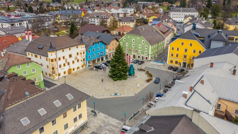 Luftaufnahme eines malerischen Stadtplatzes mit bunten Gebäuden und einem großen Weihnachtsbaum.