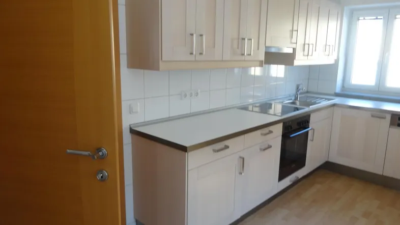 Helle Einbauküche mit hellen Holzfronten, Edelstahlspüle und Laminatboden in gutem Zustand.