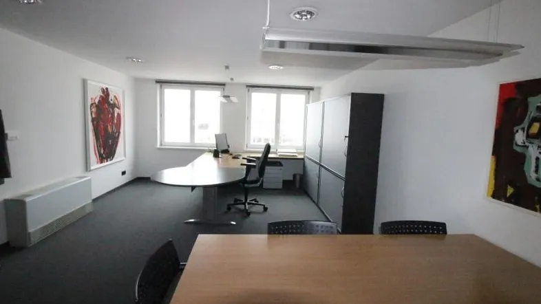 Helles Büro mit Teppichboden, modernen Möbeln und großen Fenstern für viel Tageslicht.