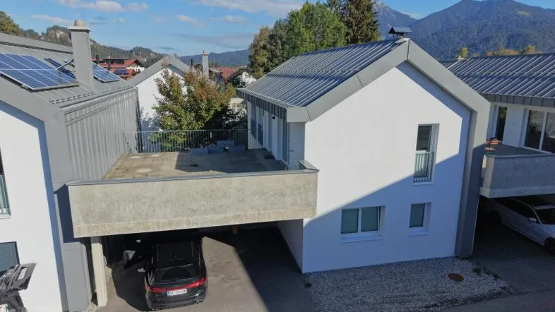Moderne Doppelhaushälfte mit großer Dachterrasse, Carport und Bergblick. Solarpaneele auf dem Dach.