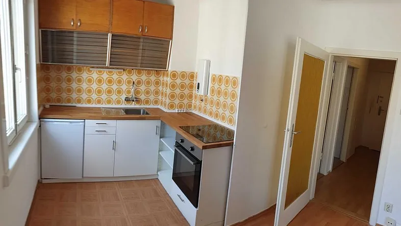 Funktionale Küche mit Holz-Arbeitsplatten, integriertem Ofen und retro-gemusterten Fliesen.