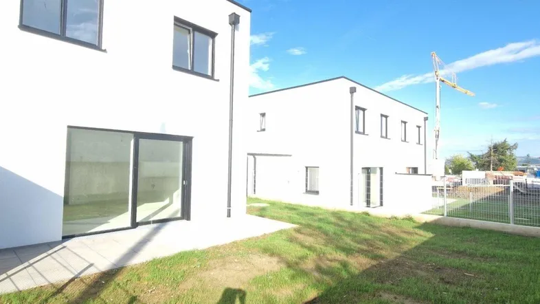 Zwei moderne, weiße Neubauten mit großen Fenstern und Terrassenbereichen unter blauem Himmel.