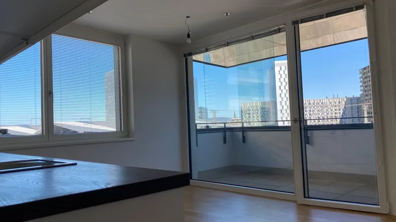 Lichtdurchfluteter Wohn-Essbereich mit Küchenzeile und Zugang zum Balkon mit Stadtblick.