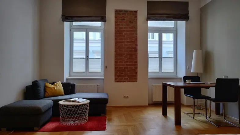 Helles Wohn- und Esszimmer mit Parkettboden, bequemer Couch und Esstisch.